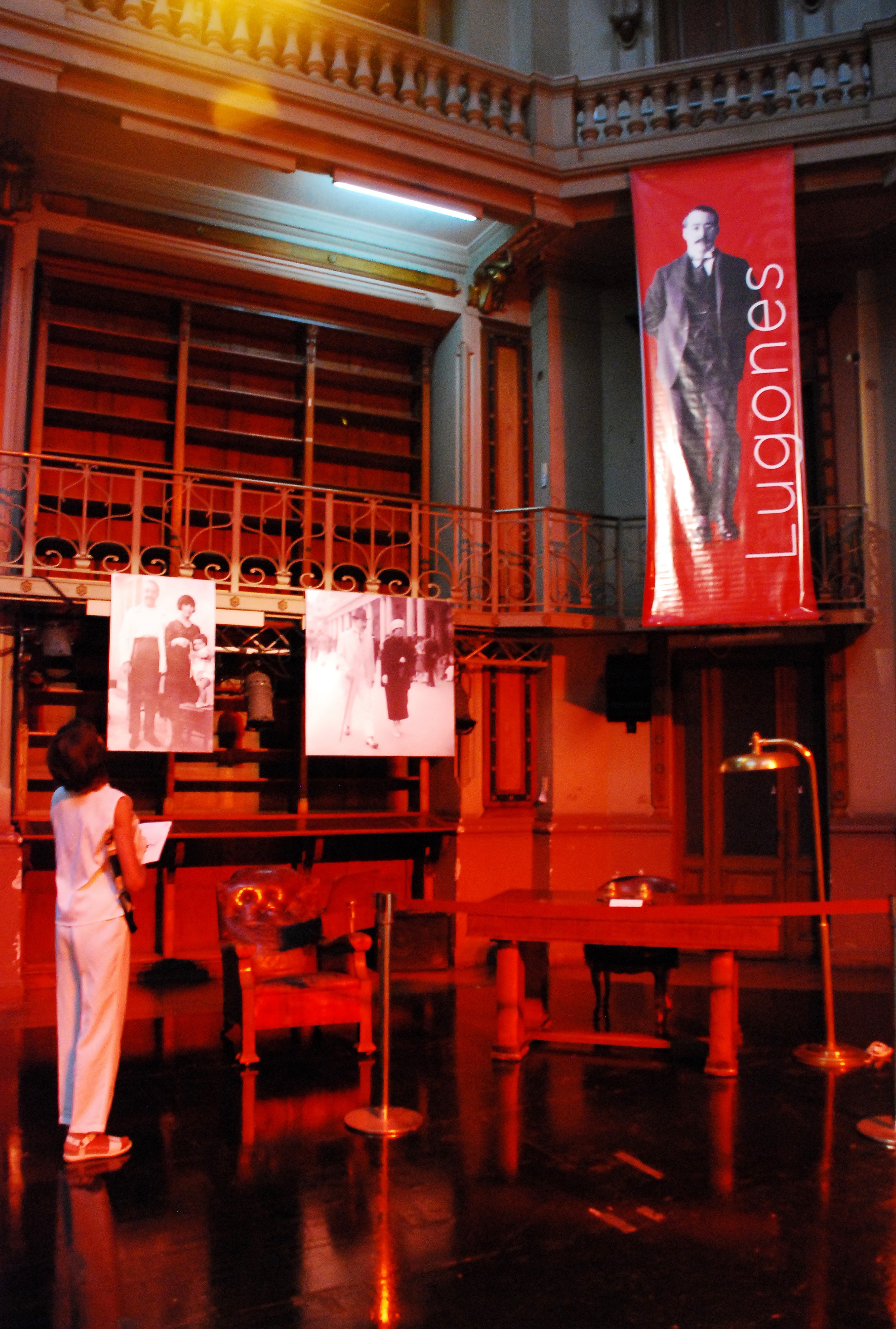 Fotografía de la exposición realizada con motivos del 80 aniversario del fallecimiento de Leopoldo Lugones Fotografía de la exposición realizada con motivos del 80 aniversario del fallecimiento de Leopoldo Lugones. Muestra el escritorio del escritor, el sillón, fotos y una persona mirando la exposición.